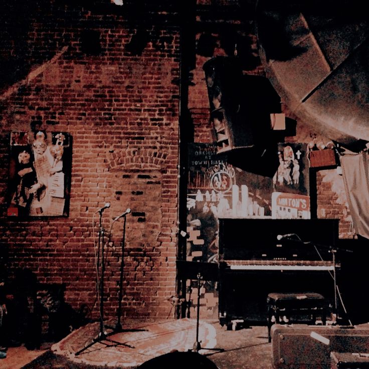 an old brick wall with posters on it and a piano in the foreground next to microphones