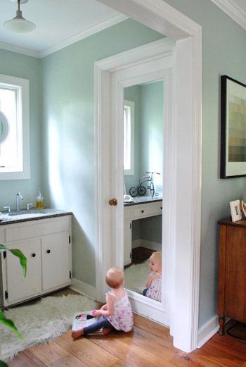 a baby sitting on the floor in front of a mirror