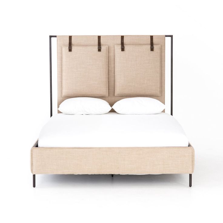 an upholstered bed with two white pillows and headboard made out of linen