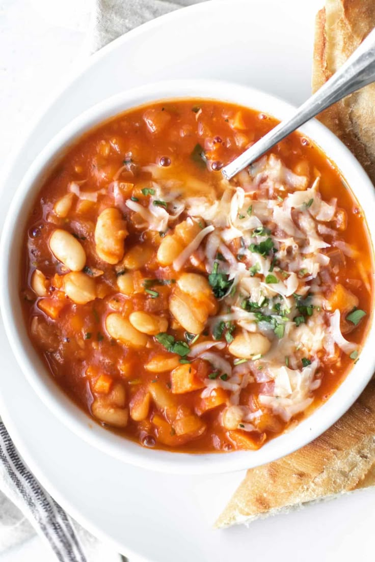 a white bowl filled with soup next to two pieces of bread