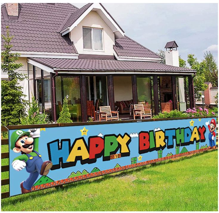 a large happy birthday sign in front of a house with a lawn and fence surrounding it