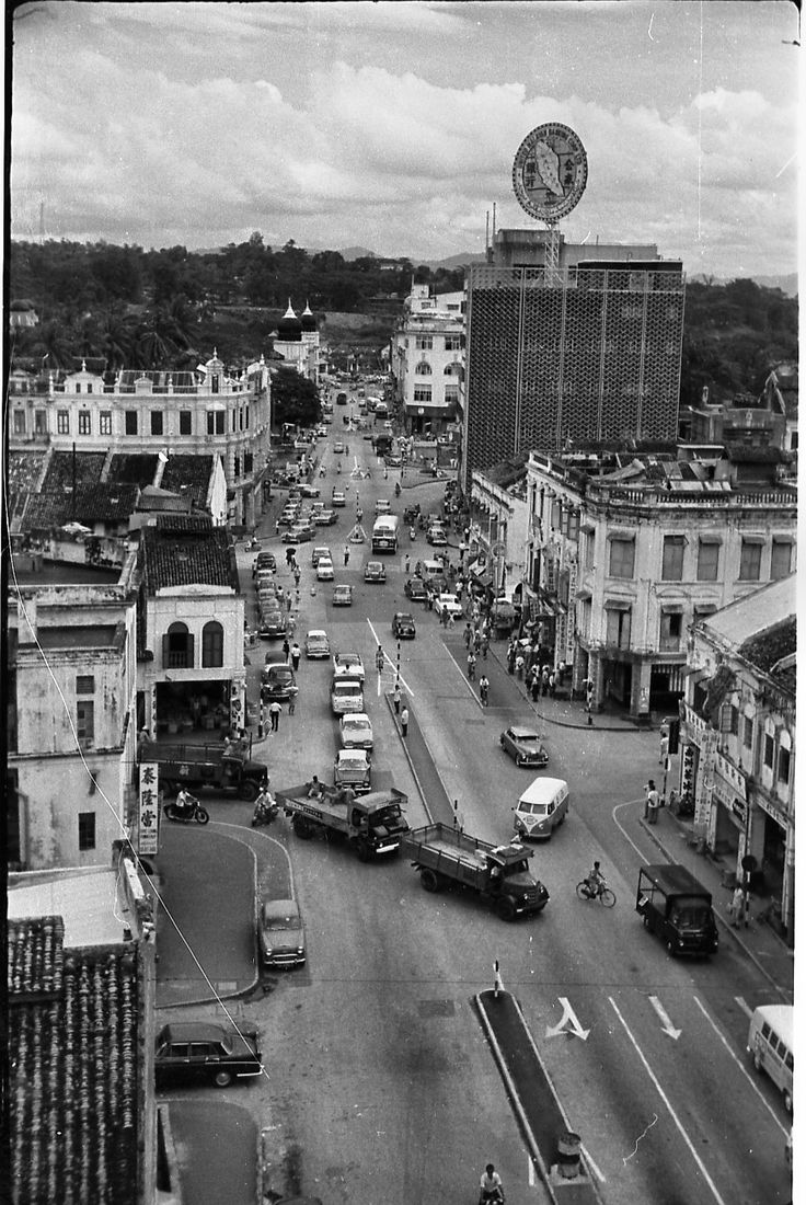 an old black and white photo of a city street with cars driving down the road