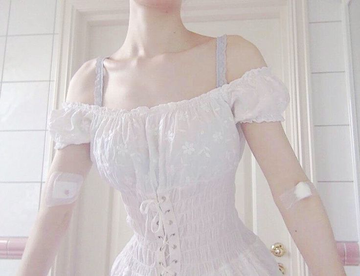 a mannequin dressed in white with gloves on her arm and hand over her shoulder