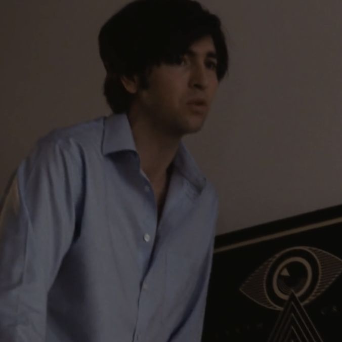 a man in a blue shirt standing next to a wall