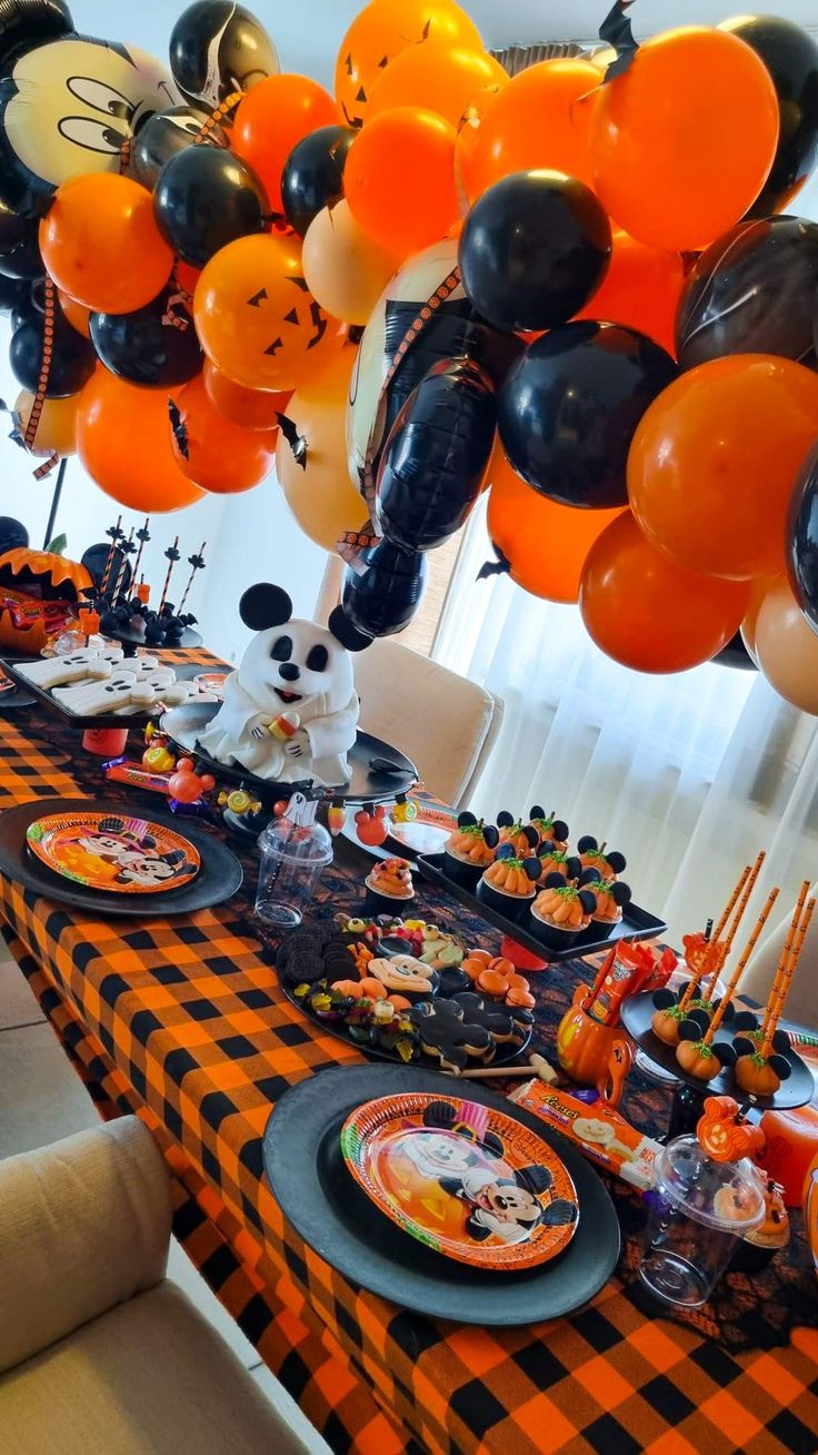 a table topped with lots of orange and black balloons