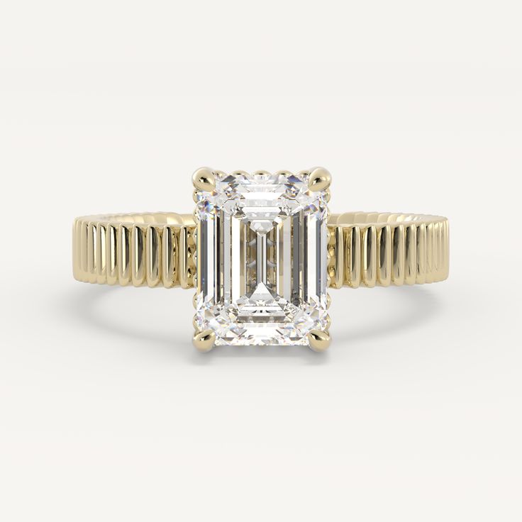 a yellow gold ring with an emerald cut diamond in the center and thin band around it