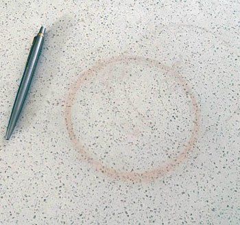 a pen sitting on top of a white counter next to a circle drawn in sand