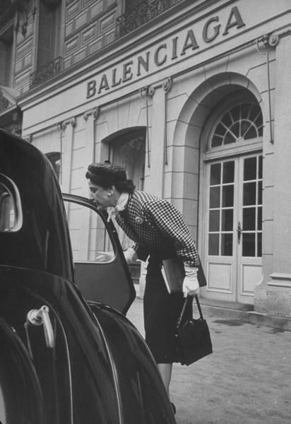 a woman leaning on the door of a car in front of a baleincia