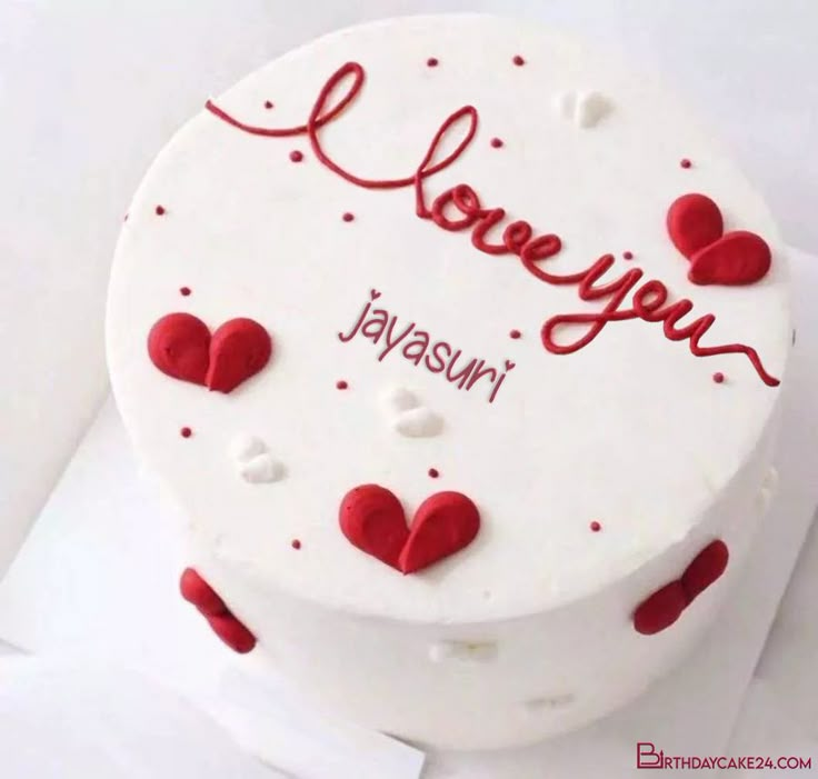 a white cake with red hearts and the words love you written on it in cursive writing