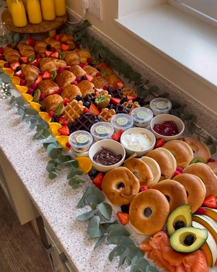 an assortment of food is displayed on a buffet table with fruit and dips in bowls