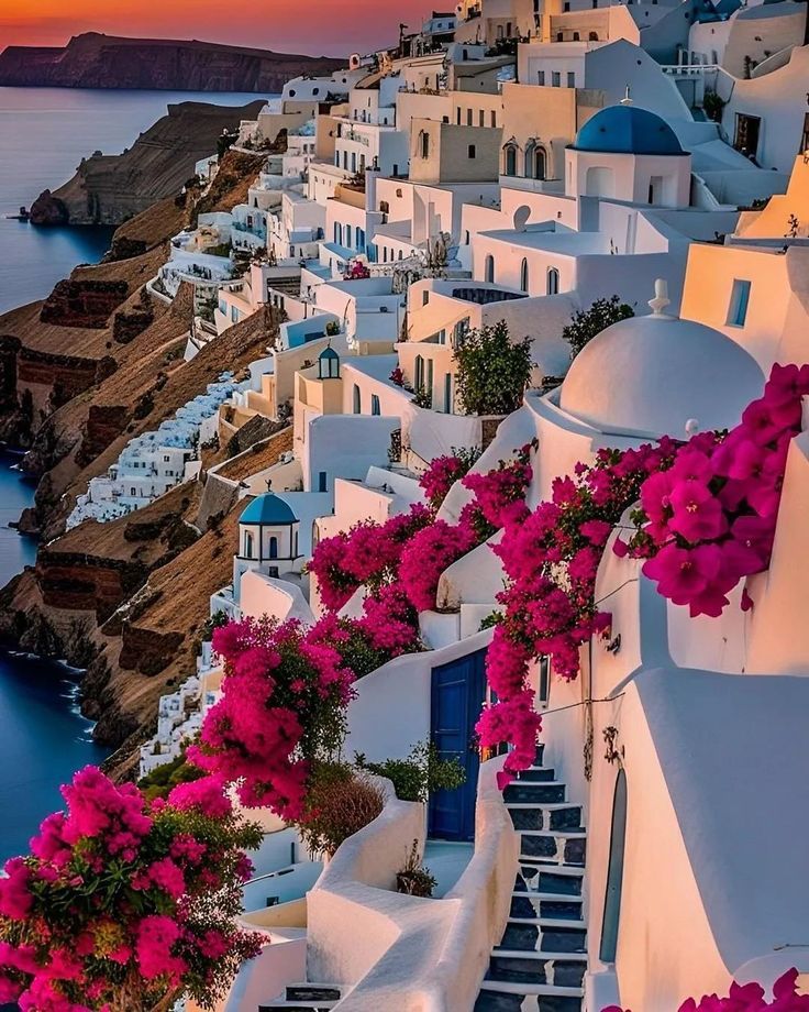 the sun is setting over some white buildings with pink flowers on them and stairs leading down to the water