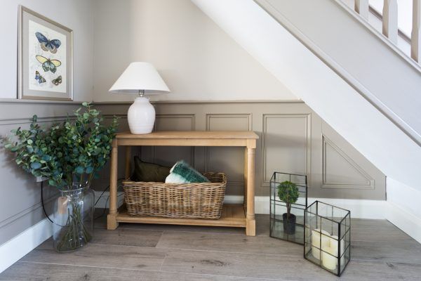 a basket and some plants on the floor in front of a stair case next to a lamp