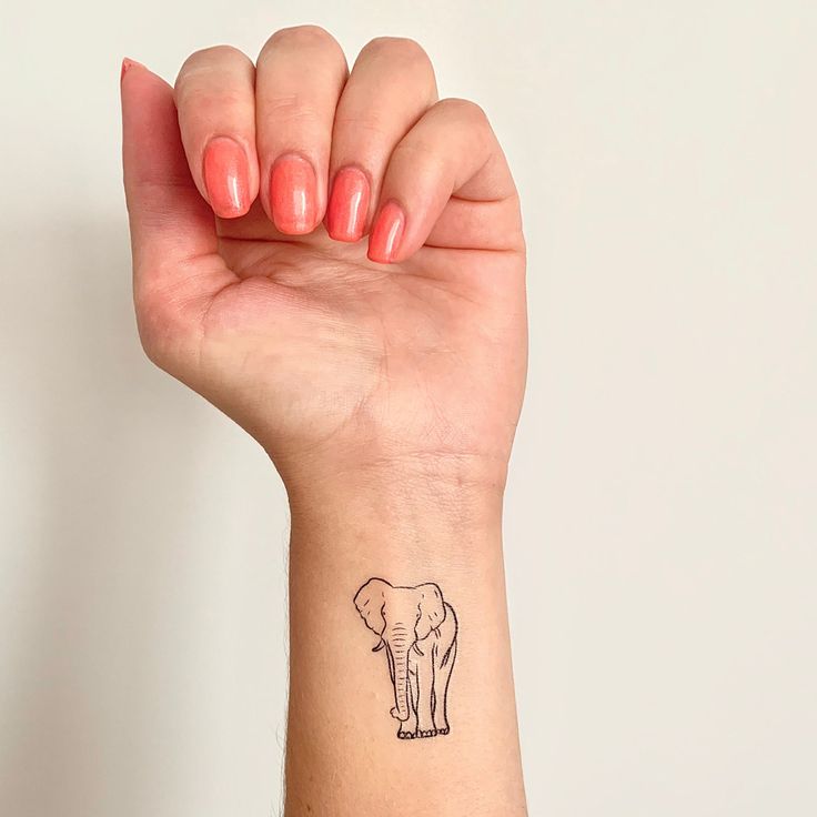 a woman's arm with a small tattoo of an elephant on the left wrist