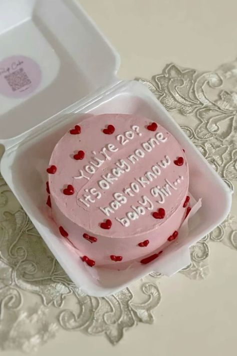 a pink cake in a white box on a lace doily with the words valentine's day written on it