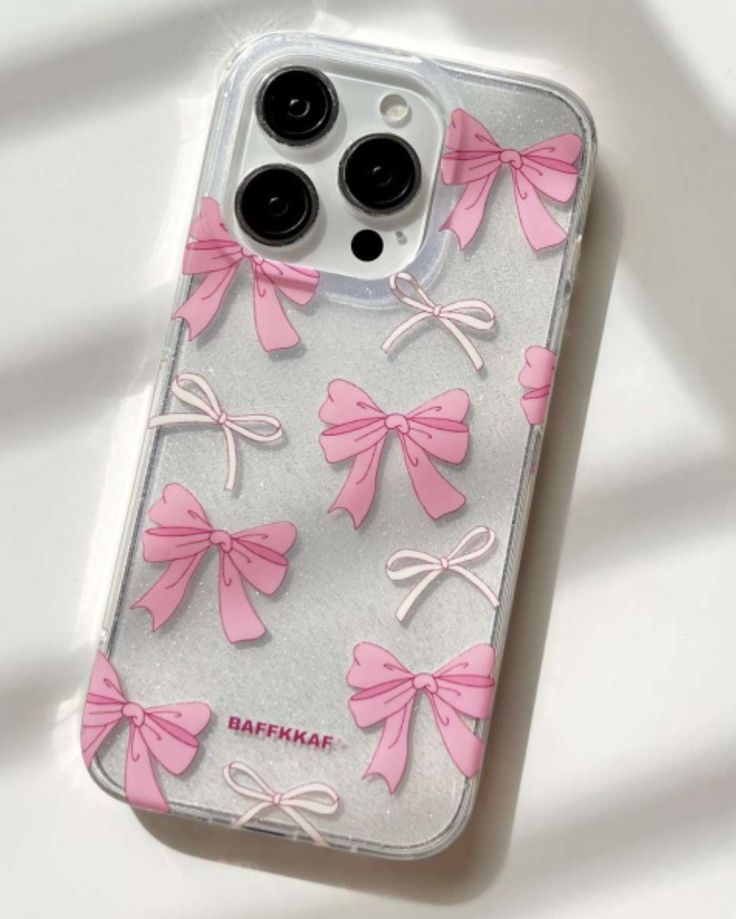 an iphone case with pink bows and black buttons on the back, sitting on a white surface