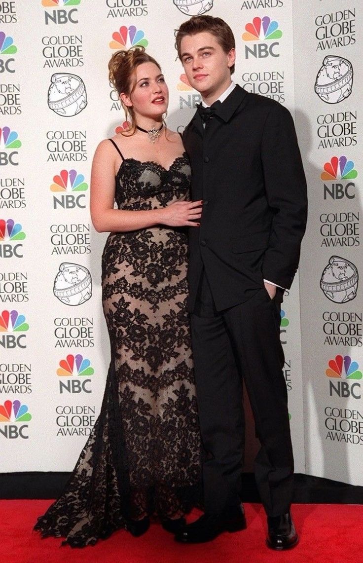 a young man and woman standing next to each other on a red carpet