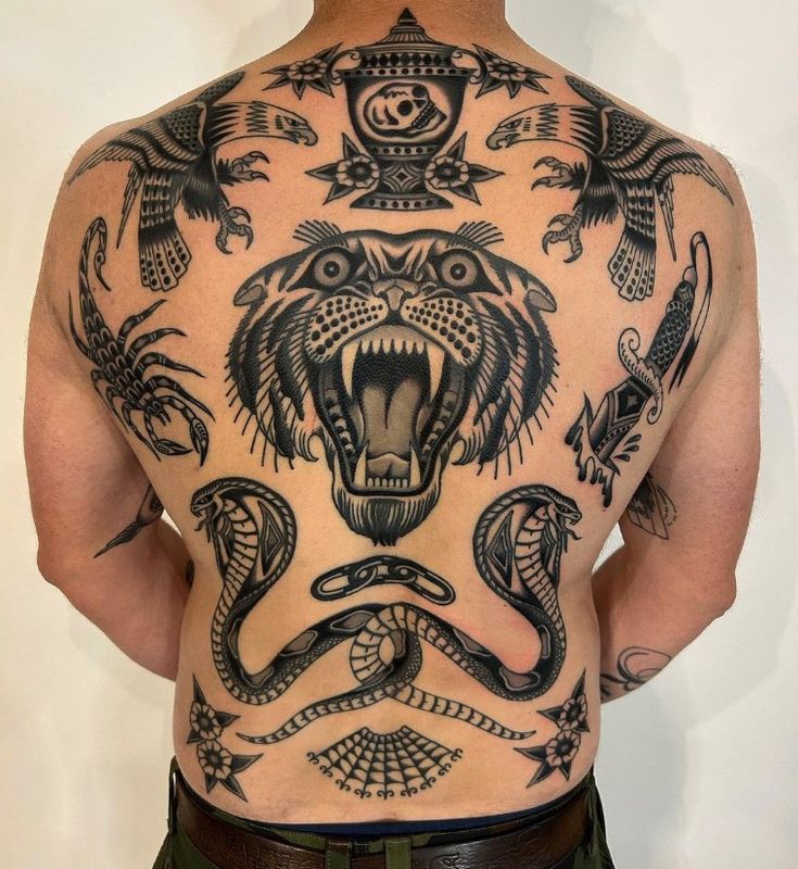 the back of a man's body with tattoos on it, including an animal and snake