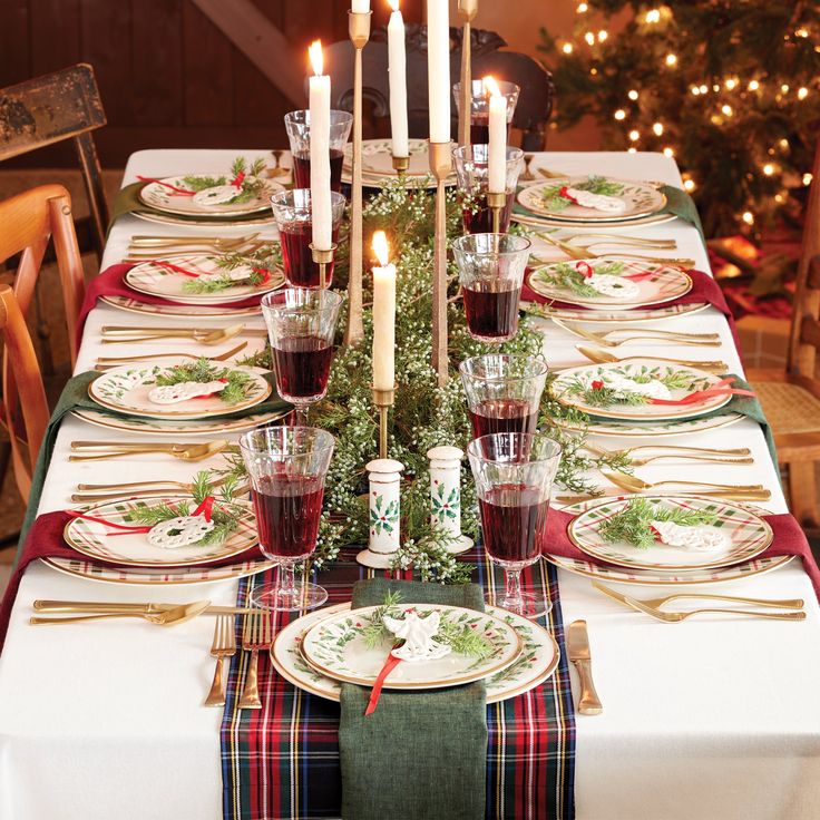 a table set for christmas dinner with candles on the top and place settings in front