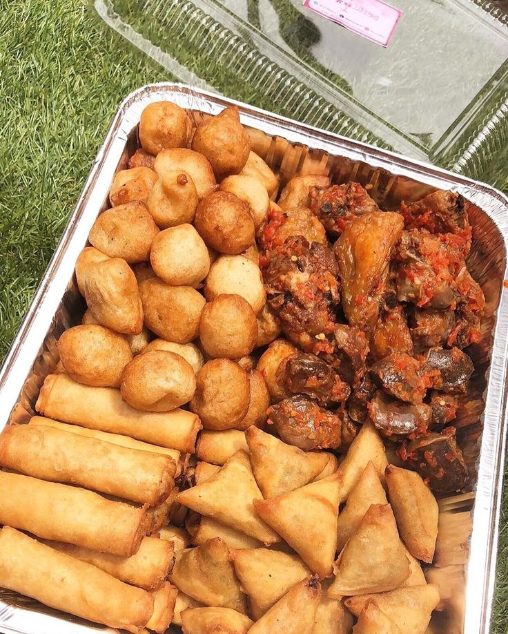 there are many different types of food in the trays on the grass, including meat rolls and dumplings