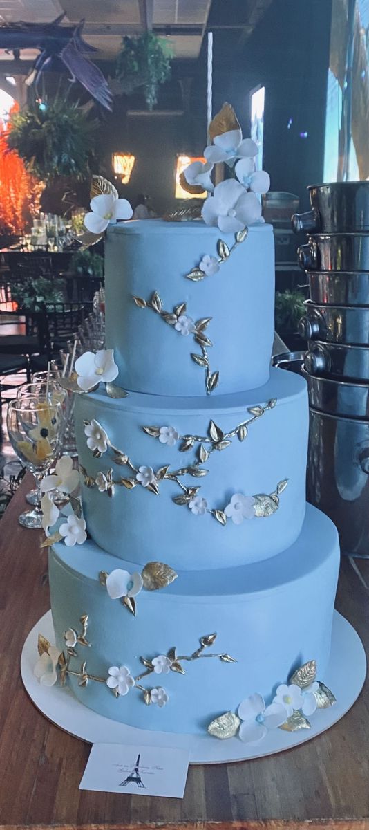 a three tiered blue cake sitting on top of a wooden table