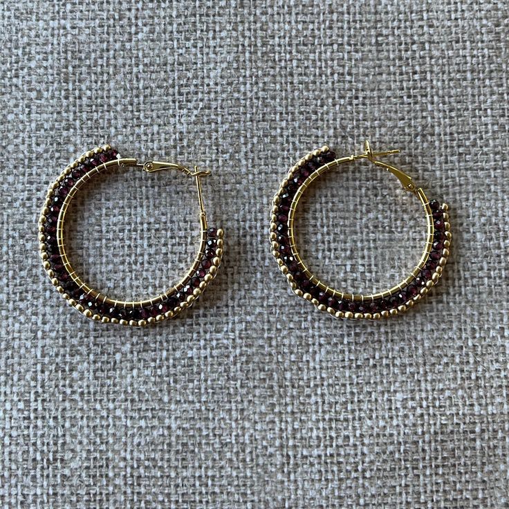 All you need is love and our Garnet Hoop Earrings. Known to increase feelings of love and devotion (and give your libido a boost!), these red-wine charmers will be admired by all. The faceted garnet beads are hand-woven on gold-plated hoop earrings and finished off with gold-colored seed beads. Garnet is the January birth stone. The lightweight hoops measure approximately 1.75 inches. Small Hoop Earrings With Dangling Beads As Gift, Small Hoop Earrings With Gold Beads As A Gift, Gold Beaded Hoop Earrings Gift, Small Hoop Jewelry With Faceted Beads For Gifts, Small Hoop Beaded Earrings With Faceted Beads For Gift, Small Hoop Earrings With Faceted Beads For Gift, Gold Bead Hoop Jewelry Gift, Adjustable Hoop Earrings With Gold Beads As Gift, Gold Beads Hoop Earrings Gift