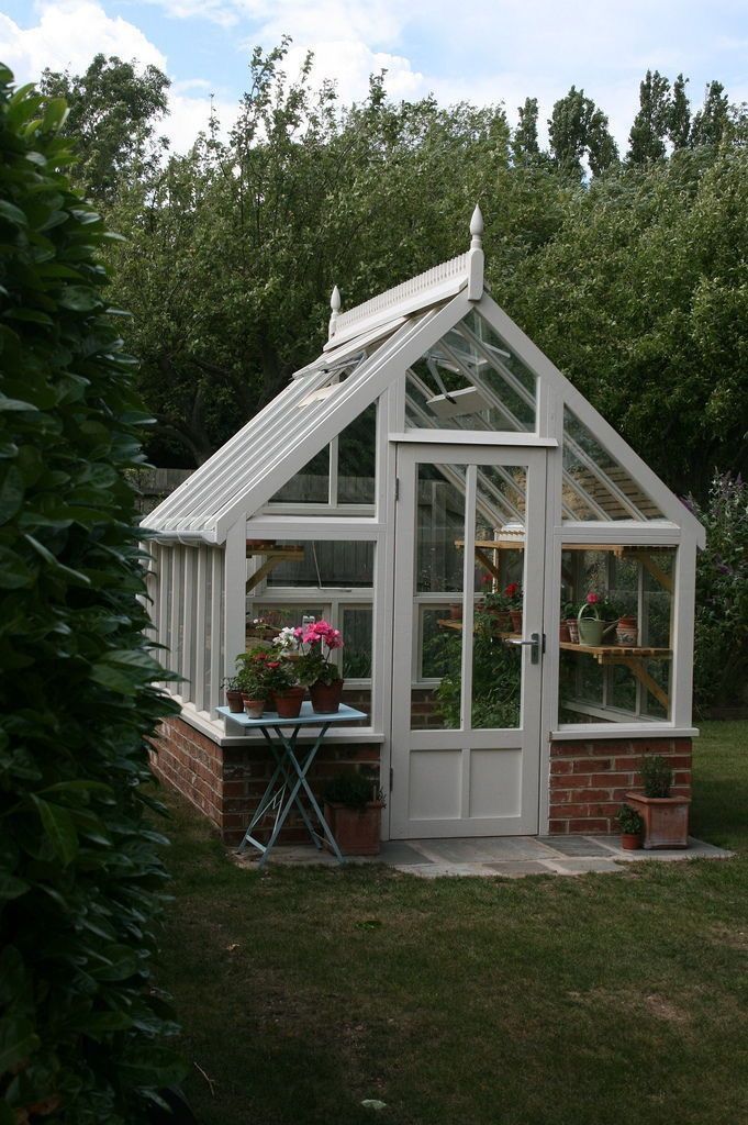 a small white greenhouse sitting in the grass