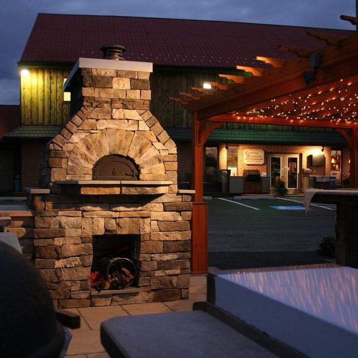 an outdoor patio with stone fireplace and seating area at night, lit up by string lights