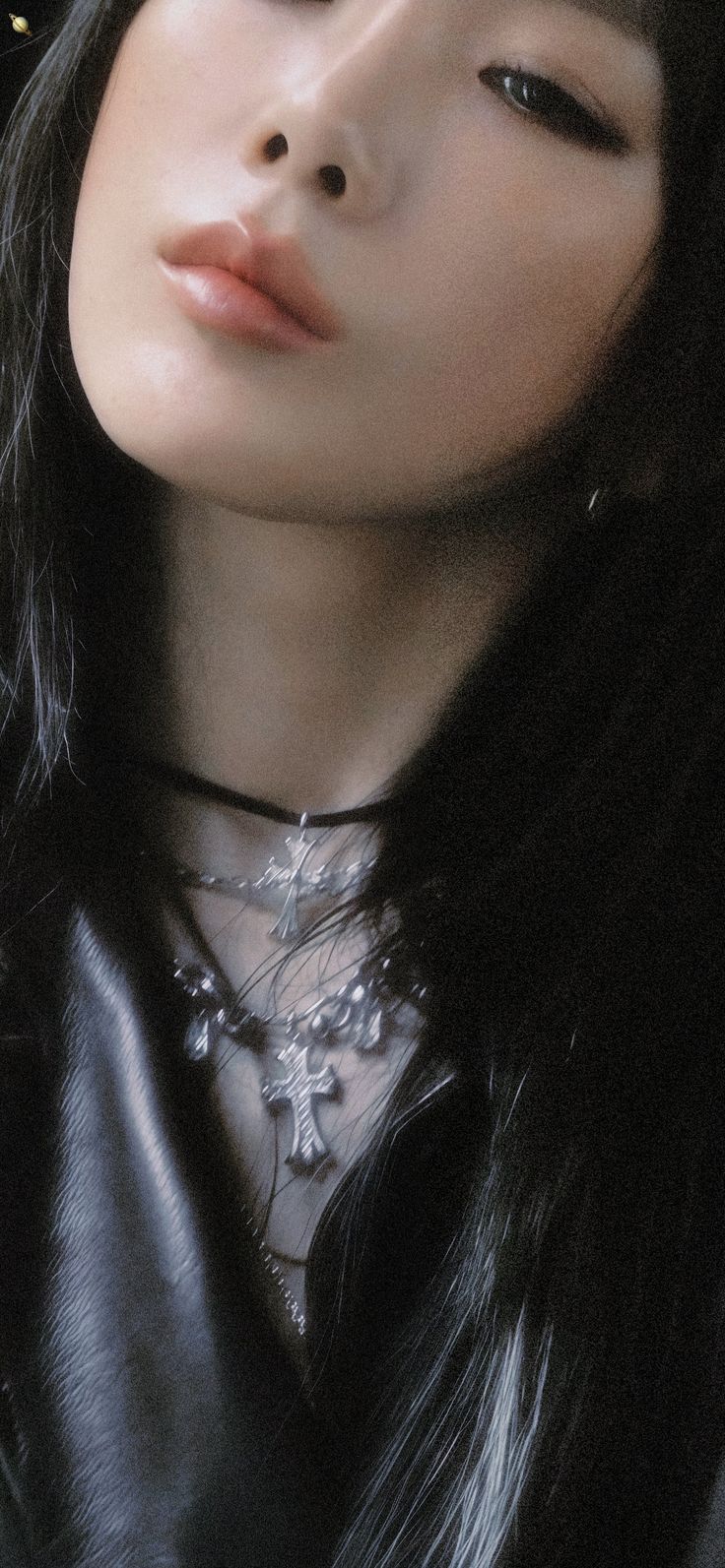 a woman with long black hair wearing a leather jacket and silver jewelry on her neck