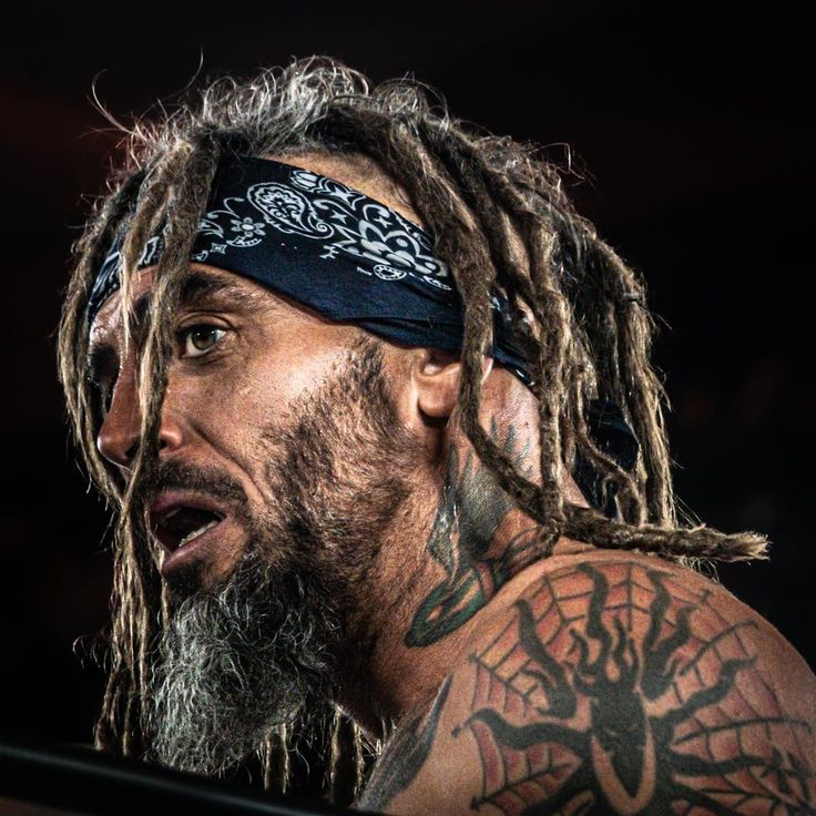 a man with dreadlocks and tattoos on his face looking off to the side