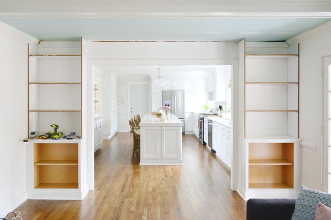 an open concept kitchen and living room with wood flooring, white walls and cabinets