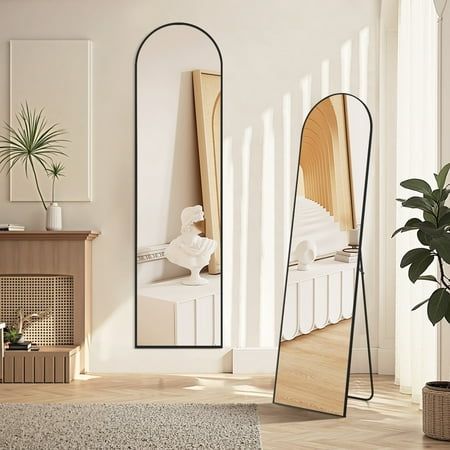 a mirror sitting on top of a wooden floor next to a plant in a room