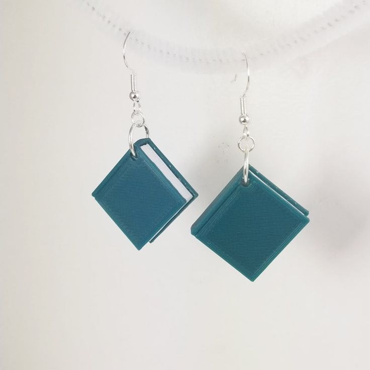 two square shaped blue earrings hanging from silver hooks