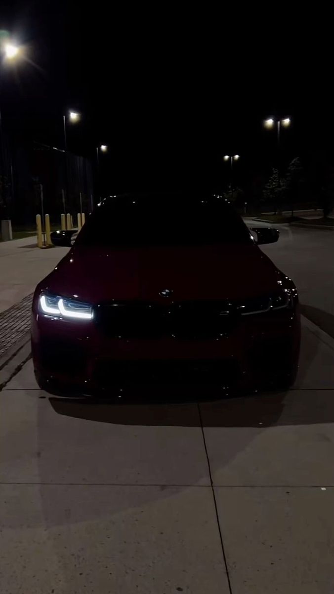 the car is parked on the side of the road at night time and it's headlights are glowing