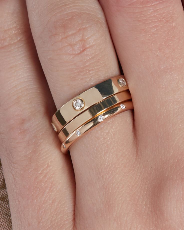 a close up of a person's hand with two rings on their wedding band