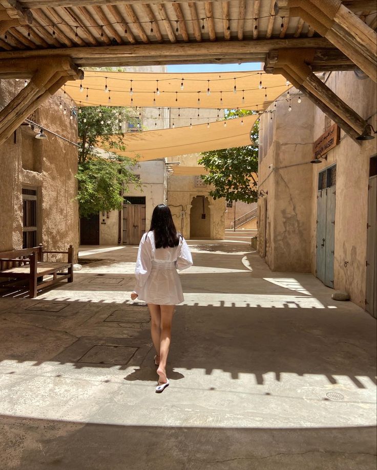 a woman is walking down an alley way