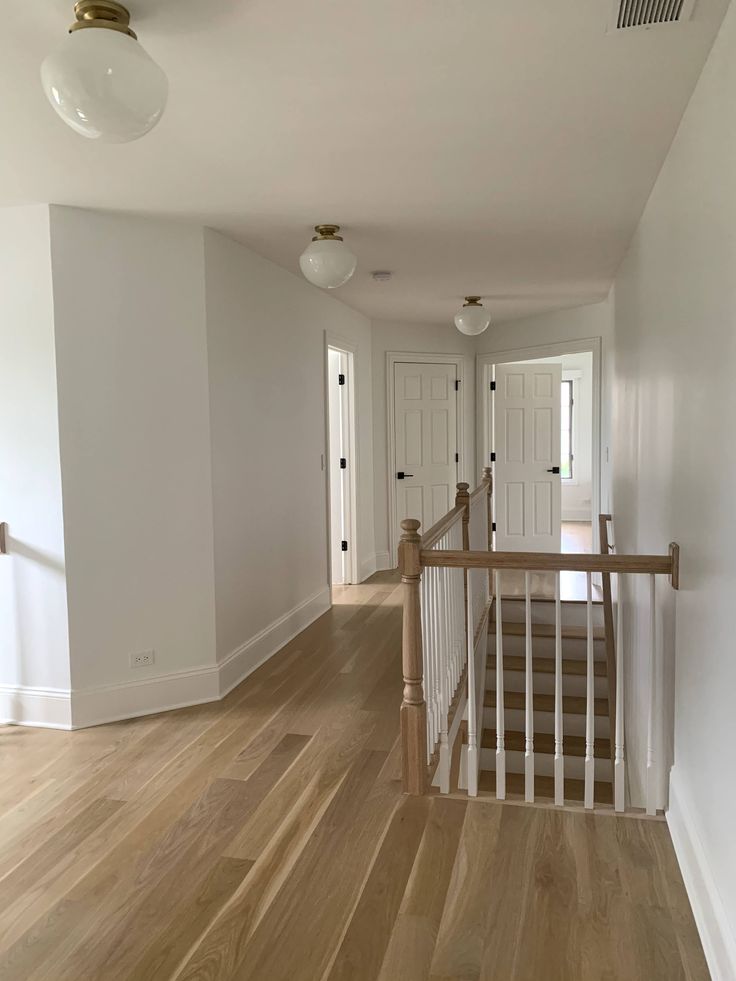 an empty hallway with wooden floors and white walls