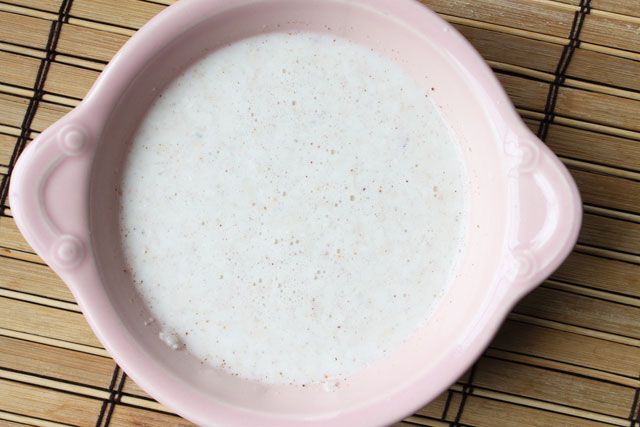 a pink bowl filled with milk sitting on top of a bamboo mat