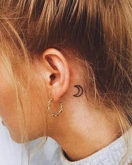 a black and white photo of a woman's ear with the moon tattoo on it