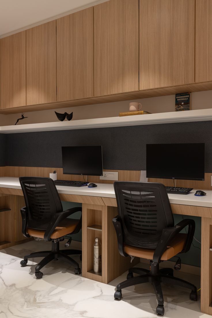 an office with two desks and three monitors