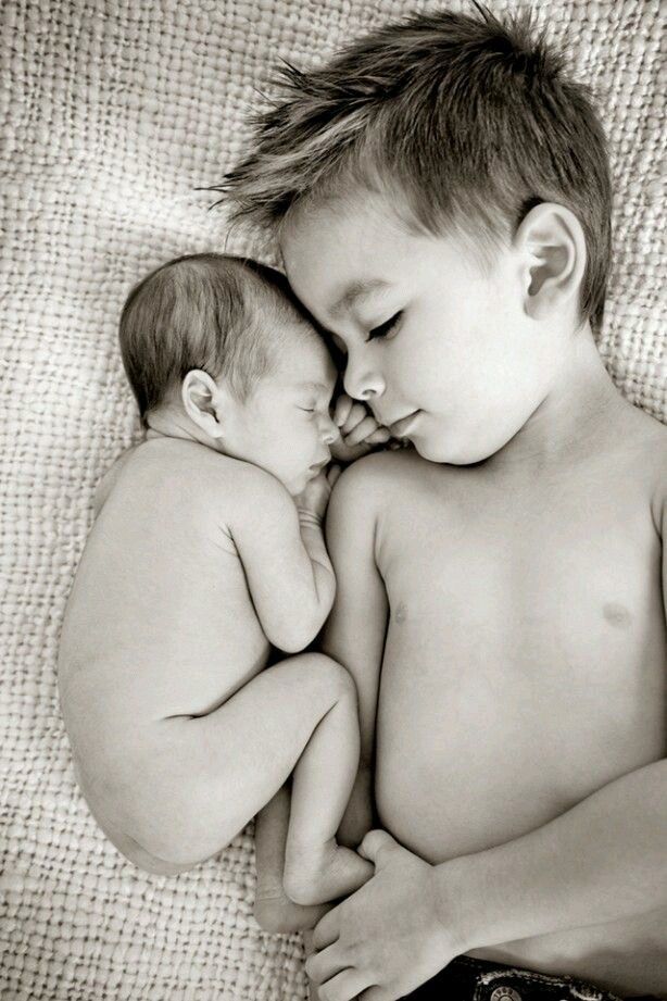 black and white photograph of two babies sleeping on top of each other with their heads together