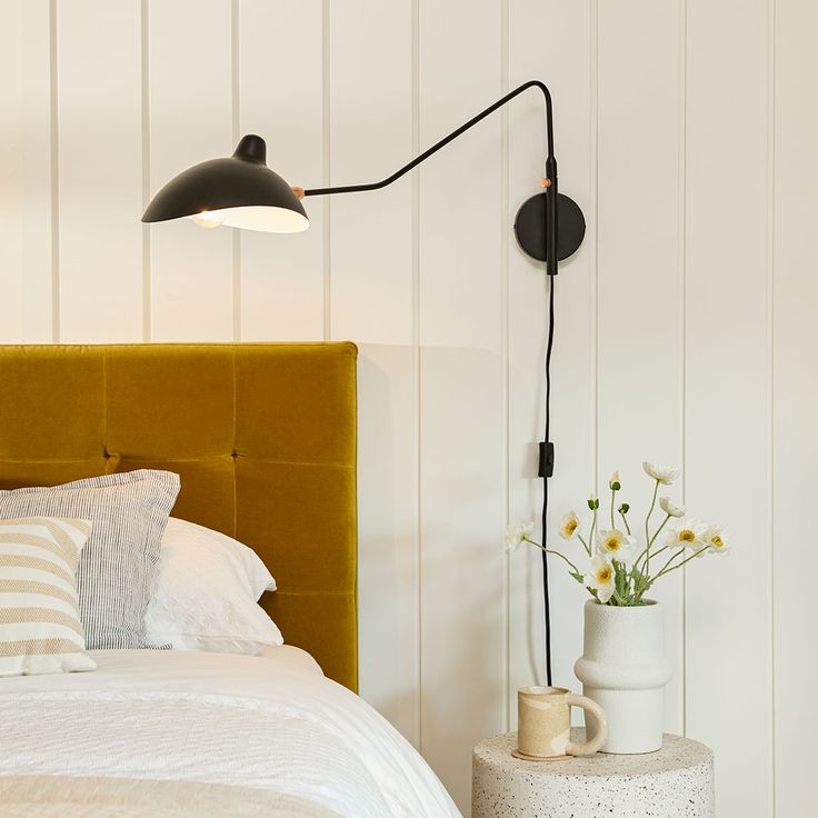 a bedroom with a bed, lamp and vase on the side table next to it