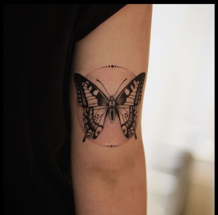 a black and white butterfly tattoo on the right arm, with dots in it's wings