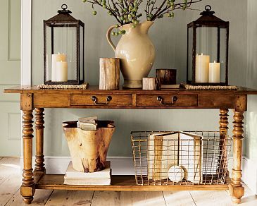 a wooden table topped with two vases filled with flowers next to candles and baskets