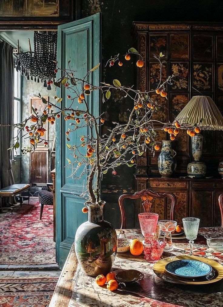 a dining room table with an orange tree in the center and vases on it