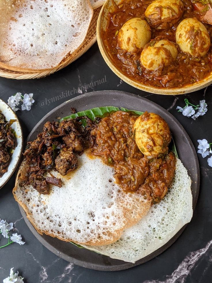 three plates with food on them sitting on a table next to bread and other dishes