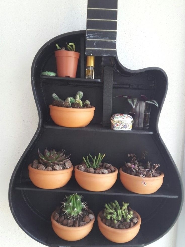 a guitar shaped shelf with potted plants on it