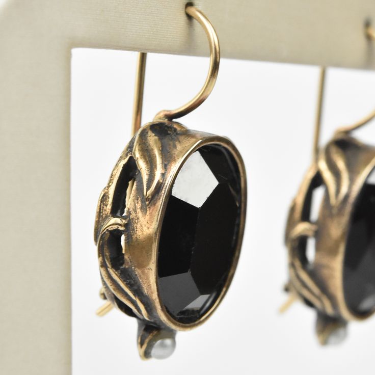 Faceted black glass stone Bronze components Pearl accents Locking french wire earring Earrings measure 1" long Made by Extasia Designer Jewelry. Goldmakers Jewelry Mission Statement Goldmakers Jewelry creates and curates a comprehensive selection of artfully designed hand-crafted jewelry. We aspire to offer the jewelry enthusiast access to affordable classics as well as fresh innovative designs. Bronze Metal Jewelry For Evening, Antique Metal Earrings For Evening, Antique Teardrop Ear Wire Jewelry, Vintage Black Jewelry With Matching Earrings, Vintage Black Metal Earrings, Black Vintage Metal Earrings, Black Crystal Metal Earrings For Formal Occasions, Antique Black Metal Jewelry, Formal Black Crystal Earrings