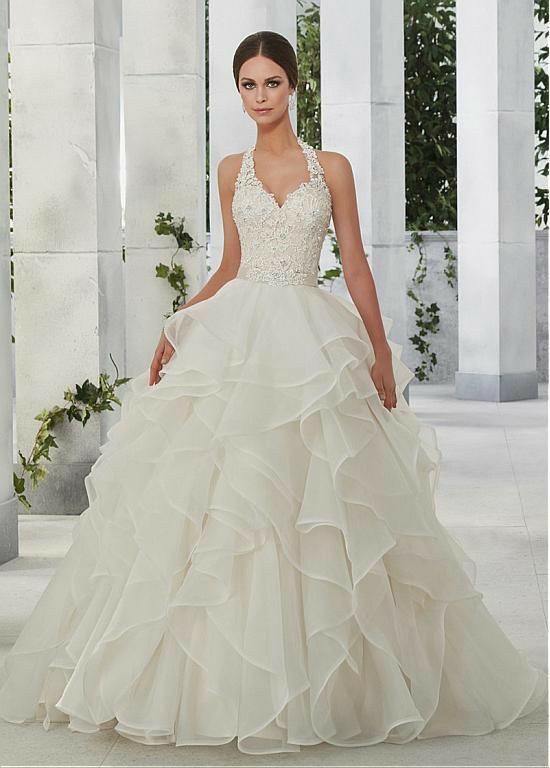 a woman in a wedding dress standing on a white floor with columns and greenery behind her