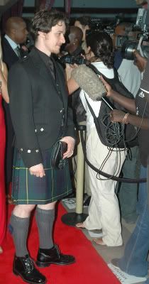 a man in a kilt standing on a red carpet with people around him and taking pictures