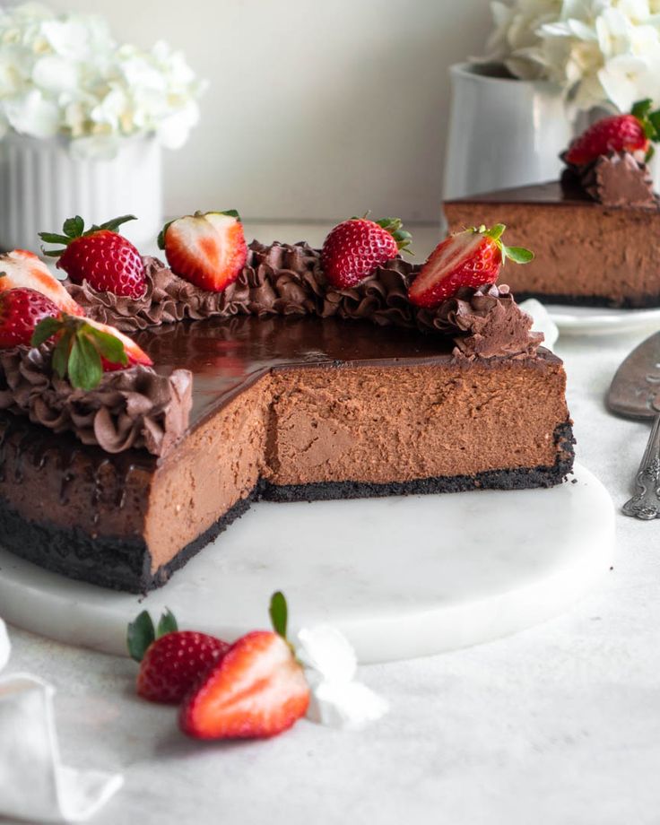 two slices of chocolate cheesecake with strawberries on the top and one slice missing